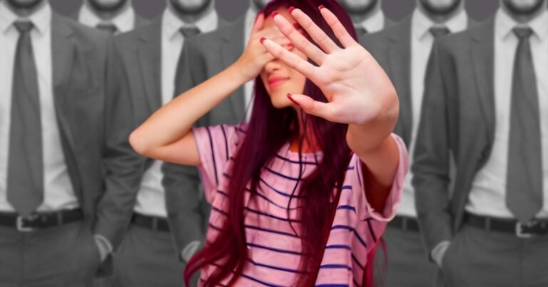 A colorful, neurodivergent woman standing in front of a row of grey suited men making a gesture of ignoring her difference